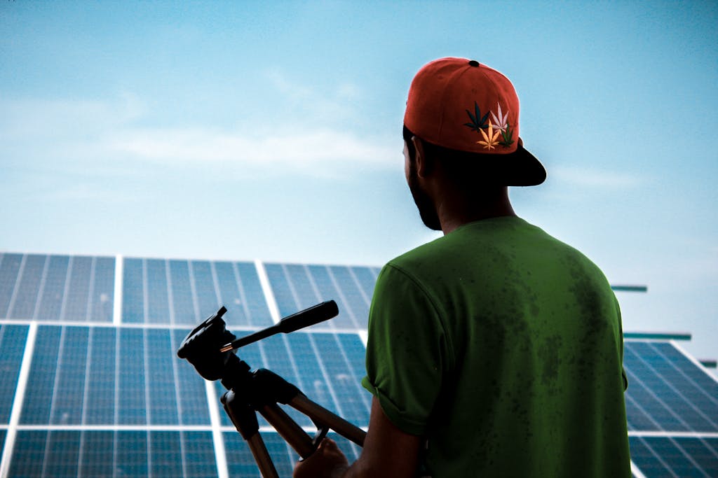 A person in a cap films a solar panel installation, promoting sustainable energy solutions.